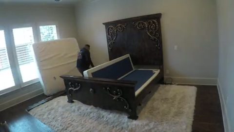 mover moving a box spring beside an ornate bedroom set