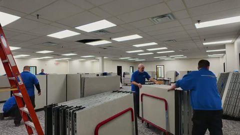 crew loading office cubicle partition panels onto wheeled carts, face visible